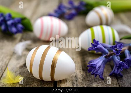 Colorful Easter eggs with feathers and blue hyacinths on a rustic wooden table. Easter concept. Stock Photo