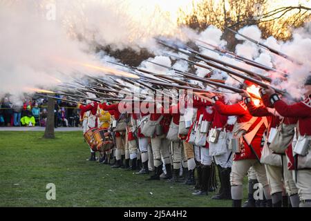 Lexington, United States of America. 18 April, 2022. Costumed historic actors playing the part of the British Regulars fire muskets during a Patriots Day reenactment April 18, 2022 in Lexington, Massachusetts. Patriots Day is a special Massachusetts state holiday commemorating the opening battle of the American Revolutionary War on April 19, 1775. Credit: Mark Herlihy/US Air Force/Alamy Live News Stock Photo