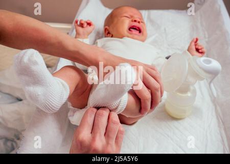 woman puts on socks and romper for baby making foot massage to her little child close up Stock Photo