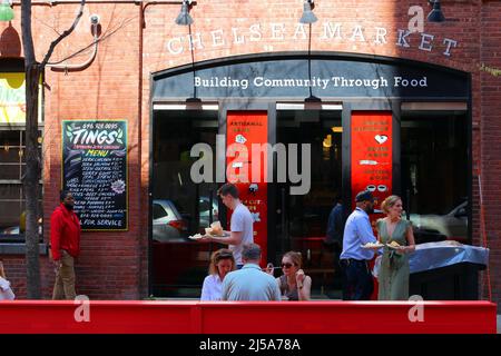 People carrying plates of food from Los Tacos No 1 food stall in the Chelsea Market look for seating outside at the W 15th St sidewalk dining area Stock Photo