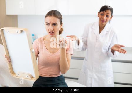 Dissatisfied woman checking result after cosmetology procedure Stock Photo