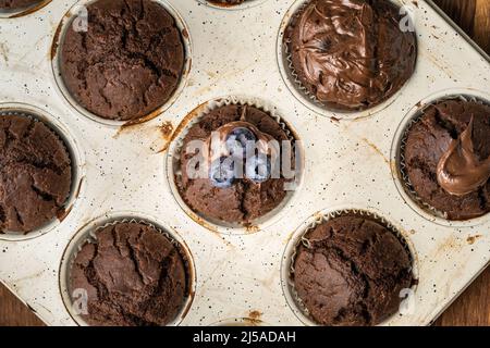 fresh baked muffins with chocolate cream and blueberries in ceramic pan top view Stock Photo