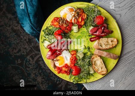 Eggs with vegetable, sausages, tomatoes, red beans and sourdough toast isolated on grey wooden background. Homemade food. Tasty breakfast. Selective f Stock Photo