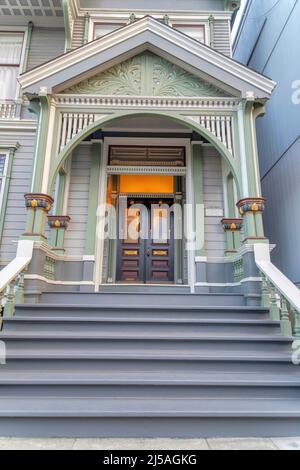 Entrance exterior of a victorian house with gray doorsteps at San Francisco, California. Porch with arched colums with ornate trims and a view of doub Stock Photo