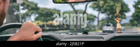 Road trip travel vacation man driving view from inside de car of the driver holding steering wheel and windshield with hula doll on dashboard Stock Photo