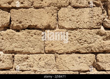 Texture of uneven stone brick wall in sunlight Stock Photo
