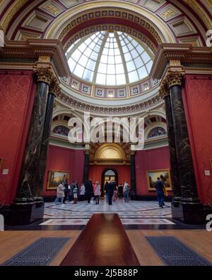London, Greater London, England, April 09 2022: Inside the National Gallery art museum with impressive architecture as people view the artwork. Stock Photo