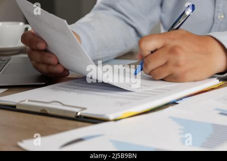 Businessman working reading documents signing contract on paper business document working on laptop computer on desk close up Stock Photo