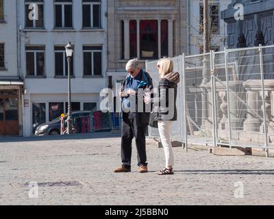 Antwerp, Belgium, April 17, 2022, Couple standing on the market square of Antwerp looking at their smartphone in search of more touristic attractions Stock Photo