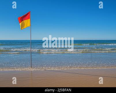 Beach with red and yellow safe swimming flag in Australia Stock Photo