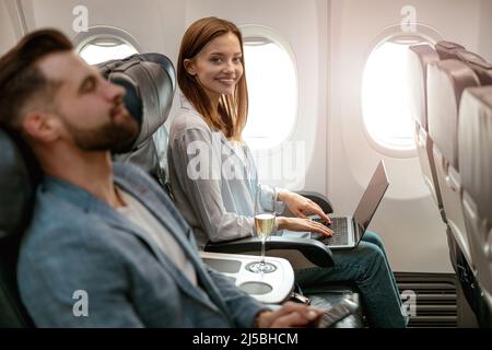Joyful woman working on notebook in airplane Stock Photo