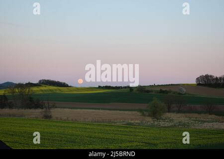full moon rising during blue hour Stock Photo