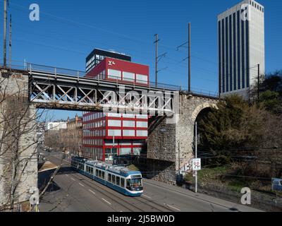 Zurich, Switzerland - March 5th 2022: A Tram train crossing below a railway bridge in a business district Stock Photo