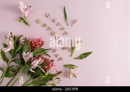 a festive composition for Mother's Day from beautiful spring flowers and inscriptions in wooden letters. pink background. top view Stock Photo