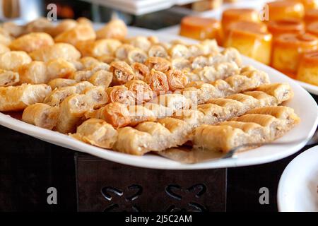 Baklava - is a layered pastry dessert made of filo pastry, filled with chopped nuts, and sweetened with syrup or honey. Dessert table in a Turkish hot Stock Photo