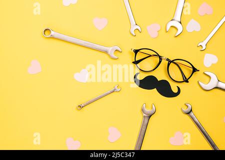 Creative holiday concept made with transparent glasses, stylish black paper photo booth props moustaches, combination wrenches and many little hearts Stock Photo