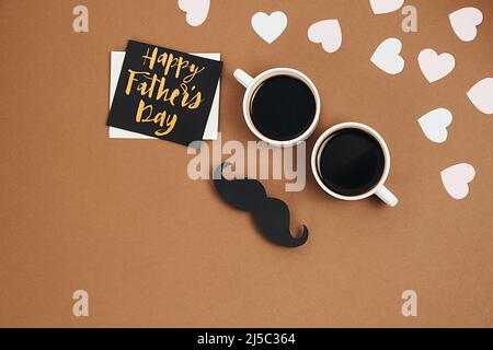 Flat lay composition with little hearts, two cup coffee, card with phrase happy father's day, retro stylish black paper photo booth props moustaches o Stock Photo