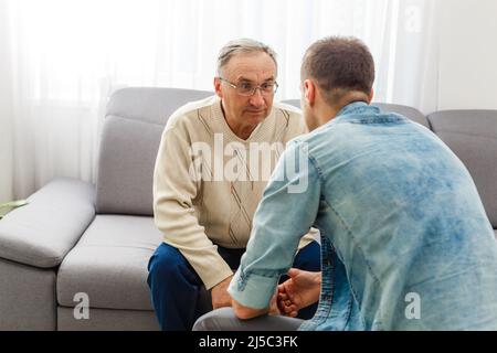 Adult Son Talking To Depressed Father At Home Stock Photo