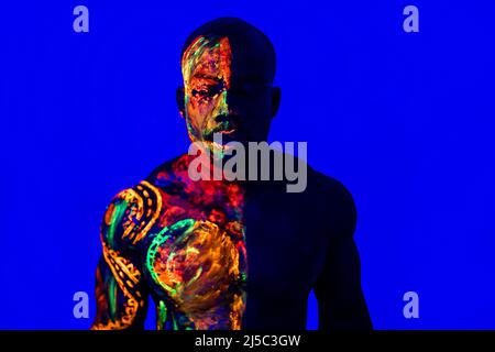 Handsome guy with UV body art close his face Stock Photo by