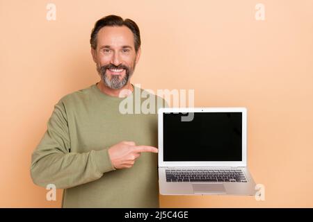 Portrait of attractive trendy cheerful man demonstrating laptop copy space ad isolated over beige pastel color background Stock Photo