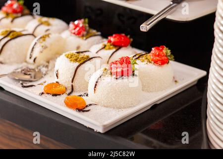 Turkish dessert milk pudding sprinkled with coconut flakes. Dessert table in a Turkish hotel. Various cakes and sweets on buffet. Stock Photo