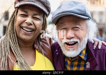 Happy multiracial senior couple having fun in city - Elderly people and love relationship concept Stock Photo