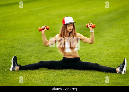 Athletic woman doing stretching at the stadium, training arms with dumbbells, practice sport, sporty girl posing with muscles, recommended healthy Stock Photo