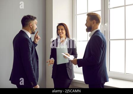 Group of happy business colleagues standing in the office and having a conversation Stock Photo