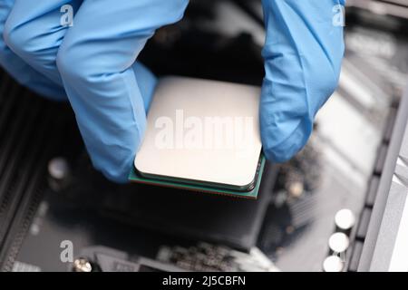 Technician examines microprocessor chip on PC motherboard Stock Photo