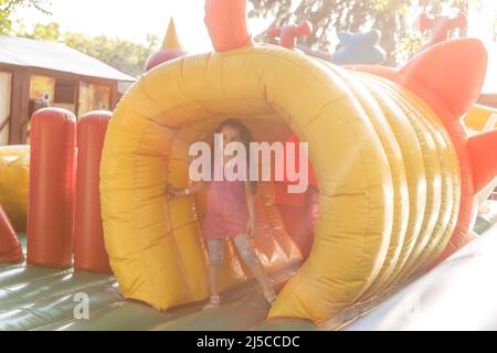 Happy little girl having lots of fun on a jumping castle during sliding Stock Photo