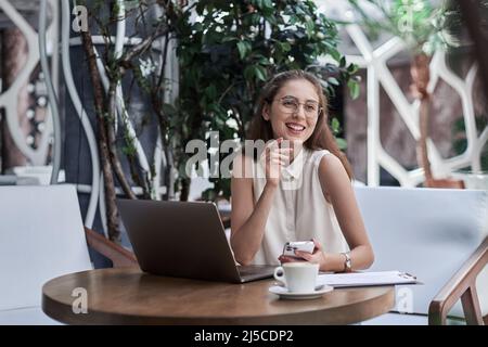 thoughtful business woman sitting in front of an open laptop in a cafe. Stock Photo