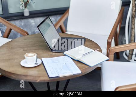 open notebook and a laptop on the table in an Internet cafe. Stock Photo