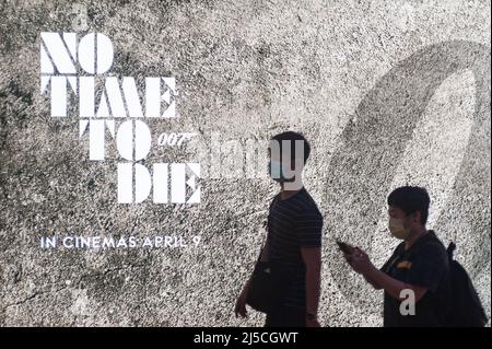 Mar. 12, 2020, Singapore, Republic of Singapore, Asia - Two people walk past a billboard advertising the new James Bond movie while wearing respirators to protect themselves from contracting the pandemic coronavirus. [automated translation] Stock Photo