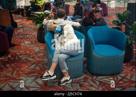 Mar. 18, 2020, Singapore, Republic of Singapore, Asia - A woman sleeps in an armchair in the arrivals area of Terminal 1 at Changi Airport. She is wearing a respirator to protect herself from contracting the pandemic coronavirus. [automated translation] Stock Photo