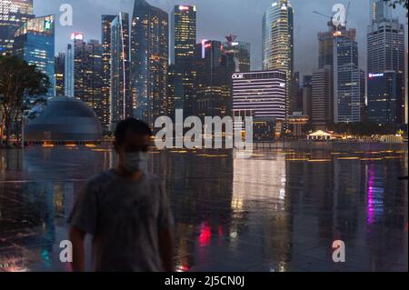 28.05.2020, Singapore, Republic of Singapore, Asia - The skyline with the skyscrapers of the business district in Marina Bay is reflected in puddles along the waterfront during a rainstorm. In the foreground, a man walks by wearing a mouth guard to protect himself from contracting the coronavirus (Covid-19). Since the introduction of the circuit breaker measures to combat the pandemic, a general mask requirement has been in place since the beginning of April as soon as people leave their homes. [automated translation]