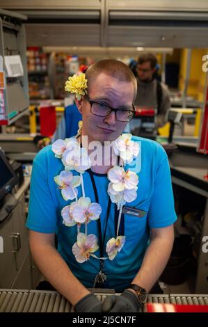 06/23/2018, Helsinki, Finland, Europe - On the occasion of midsummer, many locals decorate themselves with flower wreaths and flower necklaces like this young man working at the checkout counter of a supermarket. [automated translation] Stock Photo