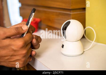 Close up shot of hands scanning smart cctv home surveillance camera on mobile phone at home - concepts of smar home, safety and security. Stock Photo