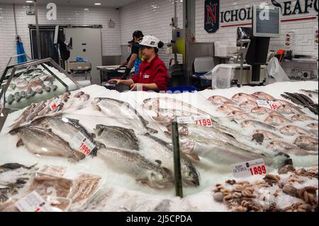 Sept. 26, 2019, Sydney, New South Wales, Australia - A saleswoman stands behind a counter with fresh fish sitting on crushed ice at a stall in the Sydney Fish Market at Blackwattle Bay in Pyrmont. [automated translation] Stock Photo