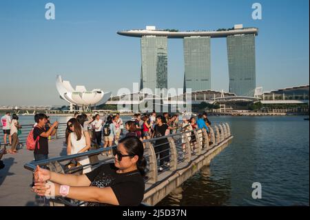18.09.2016, Singapore, Republic of Singapore, Asia - Tourists in Merlion Park on the banks of the Singapore River in Marina Bay with the three skyscraper towers of the Marina Bay Sands Hotel and the ArtScience Museum in the background. [automated translation] Stock Photo