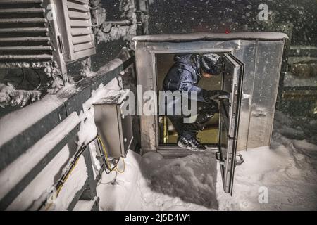 Weather officer Julian Merker from the German Weather Service on the Zugspitze starts his night shift in the evening. On the roof of the weather station, he checks the measuring instruments and clears them of snow and ice. [automated translation] Stock Photo