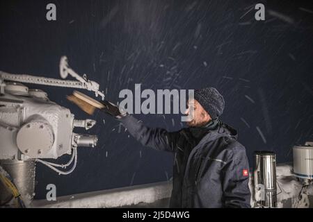 Weather warden Julian Merker from the German Weather Service on the Zugspitze starts his night shift in the evening. On the roof of the weather station, he checks the measuring instruments and clears them of snow and ice. [automated translation] Stock Photo
