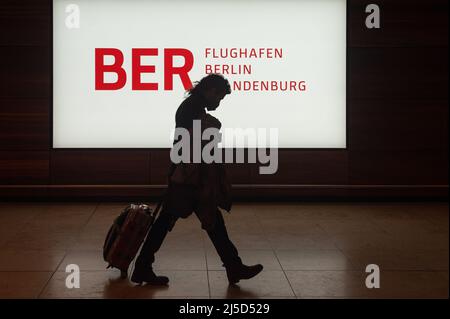 'Dec. 14, 2021, Berlin, Germany, Europe - An air traveler wearing a Corona mouth guard walks past an illuminated sign in the terminal of Berlin Brandenburg BER ''Willy Brandt'' Airport. [automated translation]' Stock Photo