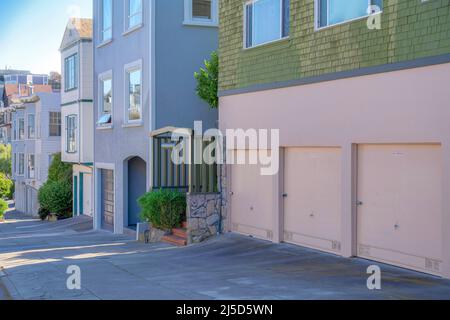 San Francisco residential buildings on a sloped street in California. There is a row of houses starting with the house on the right with green shingle Stock Photo