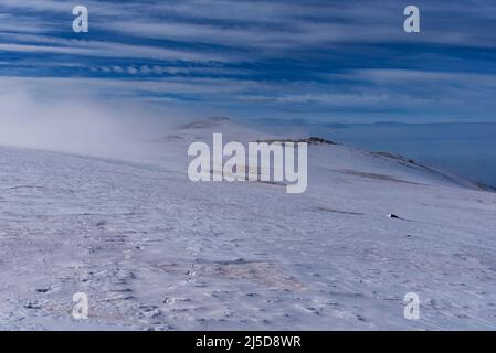 High mountain landscape, snow-covered peaks and hills, and clouds entering from the side preventing visibility, Sierra Nevada, Granada, Andalusia. Stock Photo
