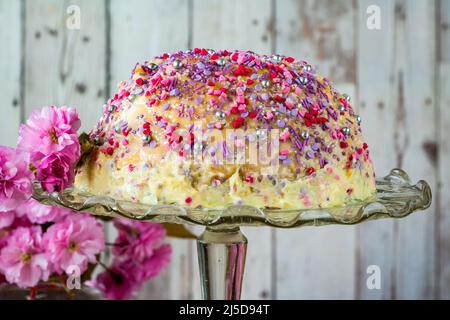 Dome cake - filled with fruity jelly, dark chocolate mousse and raspberry puree, covered with white chocolate ganache and decorated with colorful spri Stock Photo