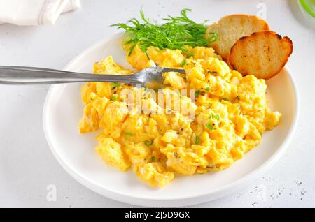 Scrambled eggs on plate over light stone background, close up Stock Photo
