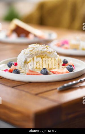 meringue roll with strawberries, blueberries, raspberries and cranberries. Dessert decorated with fresh berries on table. Stock Photo