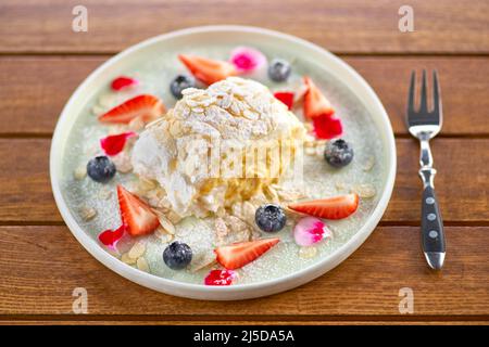 meringue roll with strawberries, blueberries, raspberries and cranberries. Dessert decorated with fresh berries on table. Stock Photo