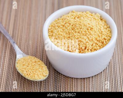 Soy lecithin in a bowl and in a teaspoon. Close up. Stock Photo