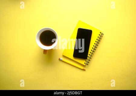 top view of smart phone and notepad on yellow  Stock Photo